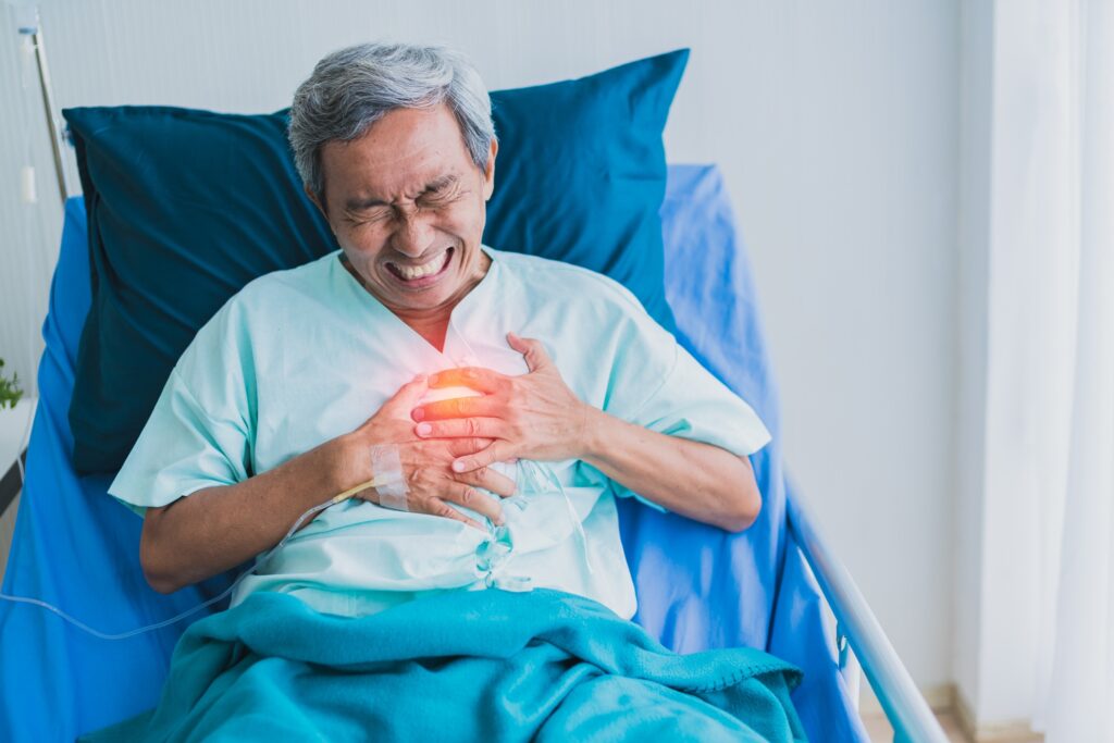 Elderly man in a hospital bed clutching his chest in pain, with a red glow over the chest area.